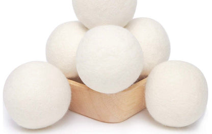 White wool dryer balls arranged around a small wooden bowl