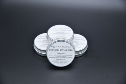 Four tattoo care balm tins arranged on a dark surface