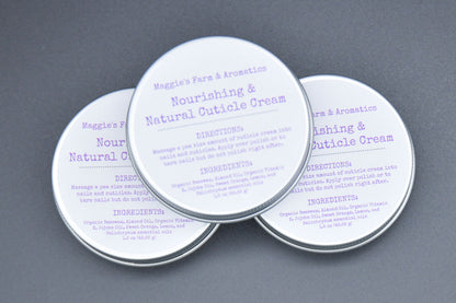 Three silver cuticle cream tins arranged on a gray background