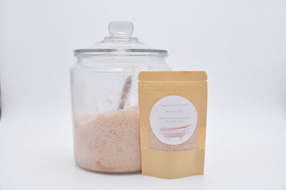Pink botanical bath salts in a pouch beside a large glass jar