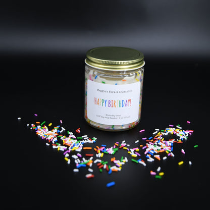 Happy Birthday soy candle in a glass jar surrounded by colorful sprinkles