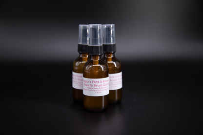 Three makeup brush cleaner spray bottles on a dark surface