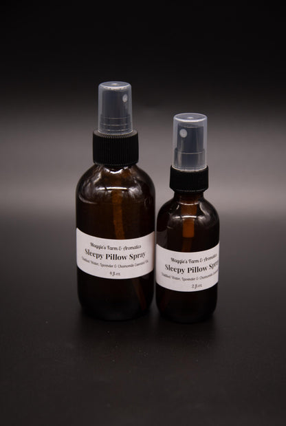 Two amber pillow and linen spray bottles on a dark surface