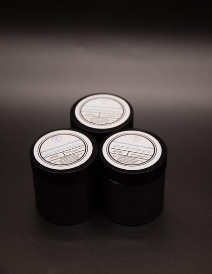 Three black jars of activated charcoal face mask arranged on a dark background