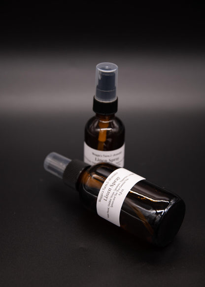 Two amber linen spray bottles arranged on a dark surface