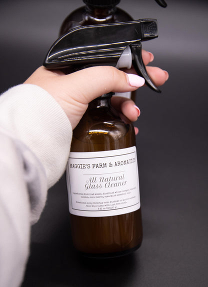 Hand holding an amber glass cleaner spray bottle