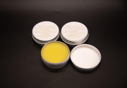 Open tin of yellow calendula salve displayed with two closed tins