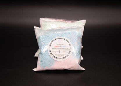 Blue and pink fizzy bath sand bag in front of two assorted bags