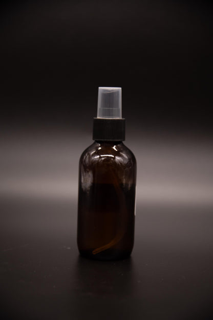 Single amber shoe spray bottle on a dark surface