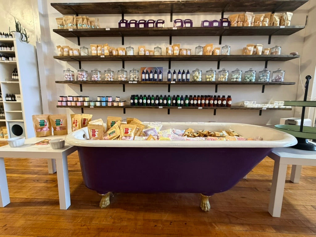 Purple bathtub display filled with handmade bath goods and home fragrance products at Maggie's Farm and Aromatics.